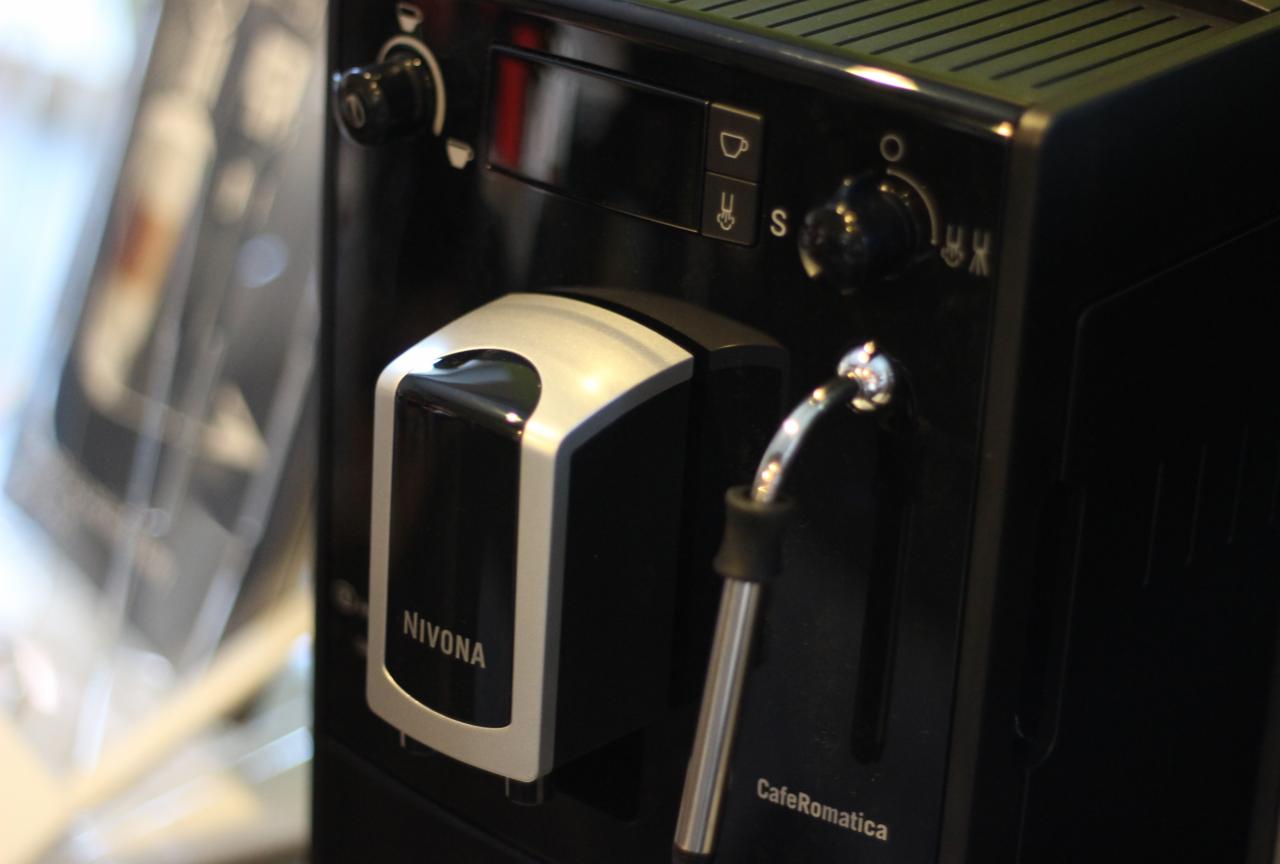 Czarny ekspres do kawy Nivona CafeRomatica z chromowanymi detalami, widoczne pokrętła i dysza do spieniania mleka.