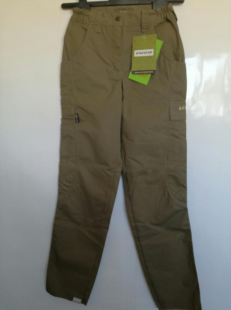 Khaki spodnie typu cargo z kieszeniami, wisząca zielona metka marki AVACUCHO, widoczne detale zamków i logo.
