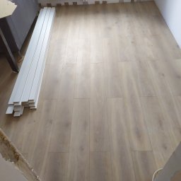 RESIN MADE ART - Jasna podłoga panelowa w trakcie montażu, widoczne listwy przypodłogowe i fragment przygotowanego narożnika ściany.