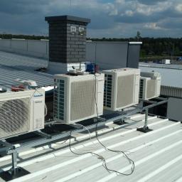 Sandblasting Mateusz Serwinek - Instalacja rzędu jednostek zewnętrznych na dachu przemysłowym, widoczne narzędzia i materiały montażowe obok pierwszego urządzenia.