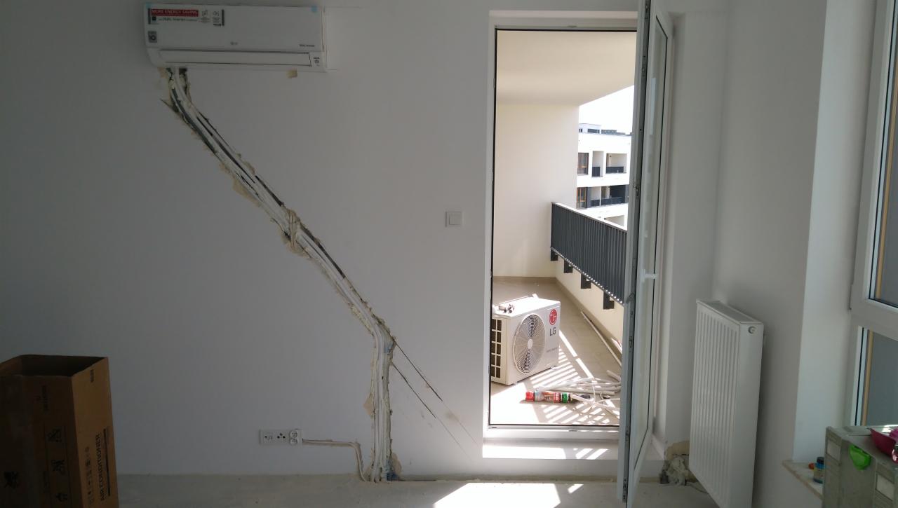 Montaż klimatyzatora LG w mieszkaniu: jednostka wewnętrzna na ścianie z bruzdami na przewody, jednostka zewnętrzna na balkonie, widoczne materiały montażowe i karton po urządzeniu.