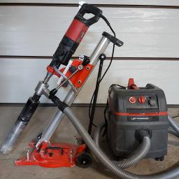 KRET-INSTAL Waldemar Szczepański - Wiertnica diamentowa Rothenberger z odkurzaczem przemysłowym Rothenberger na betonowej podłodze i tle białej bramy garażowej.