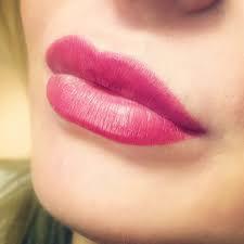 Zbliżenie na kobiece usta po zabiegu makijażu permanentnego, z widocznym efektem pełnych, intensywnie różowych warg.