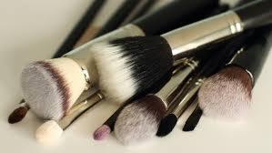 Zestaw pędzli do makijażu o różnej grubości włosia i srebrnych skuwkach, ułożonych na beżowym tle. Widoczne ślady użycia na włosiu.