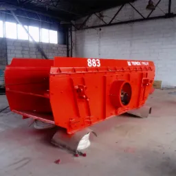 Czerwona, świeżo pomalowana proszkowo przesiewarka Terex Finlay 883, stojąca w hali produkcyjnej na podkładkach, z widocznym logo i numerem modelu.