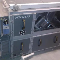 Szara centrala wentylacyjna Ventus z otwartymi drzwiczkami serwisowymi, widoczne elementy wewnętrzne, izolowane kanały wentylacyjne z boku i regulator Siemens.