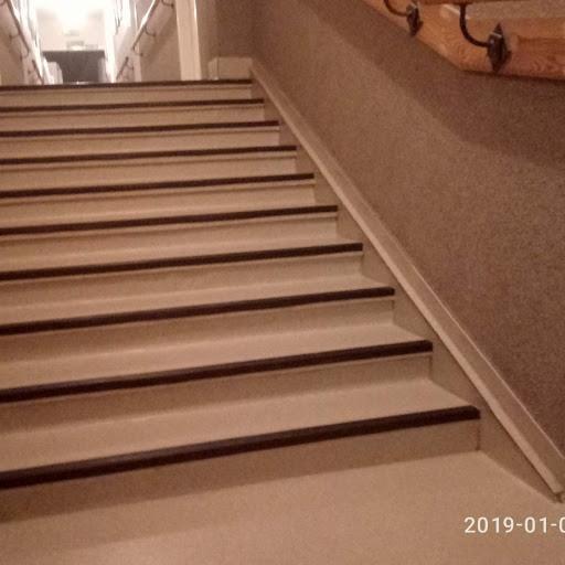 Schody pokryte wykładziną dywanową z ciemnymi listwami na krawędziach stopni, widok z dołu.