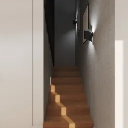 Klatka schodowa z drewnianymi schodami oświetlona nowoczesnymi kinkietami na betonowej ścianie, widok z dołu na górę.