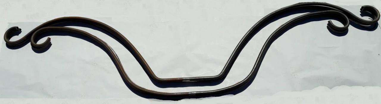 Dwie gięte, metalowe konstrukcje z zakręconymi zakończeniami, prawdopodobnie fragmenty balustrady, leżące na jasnym tle.