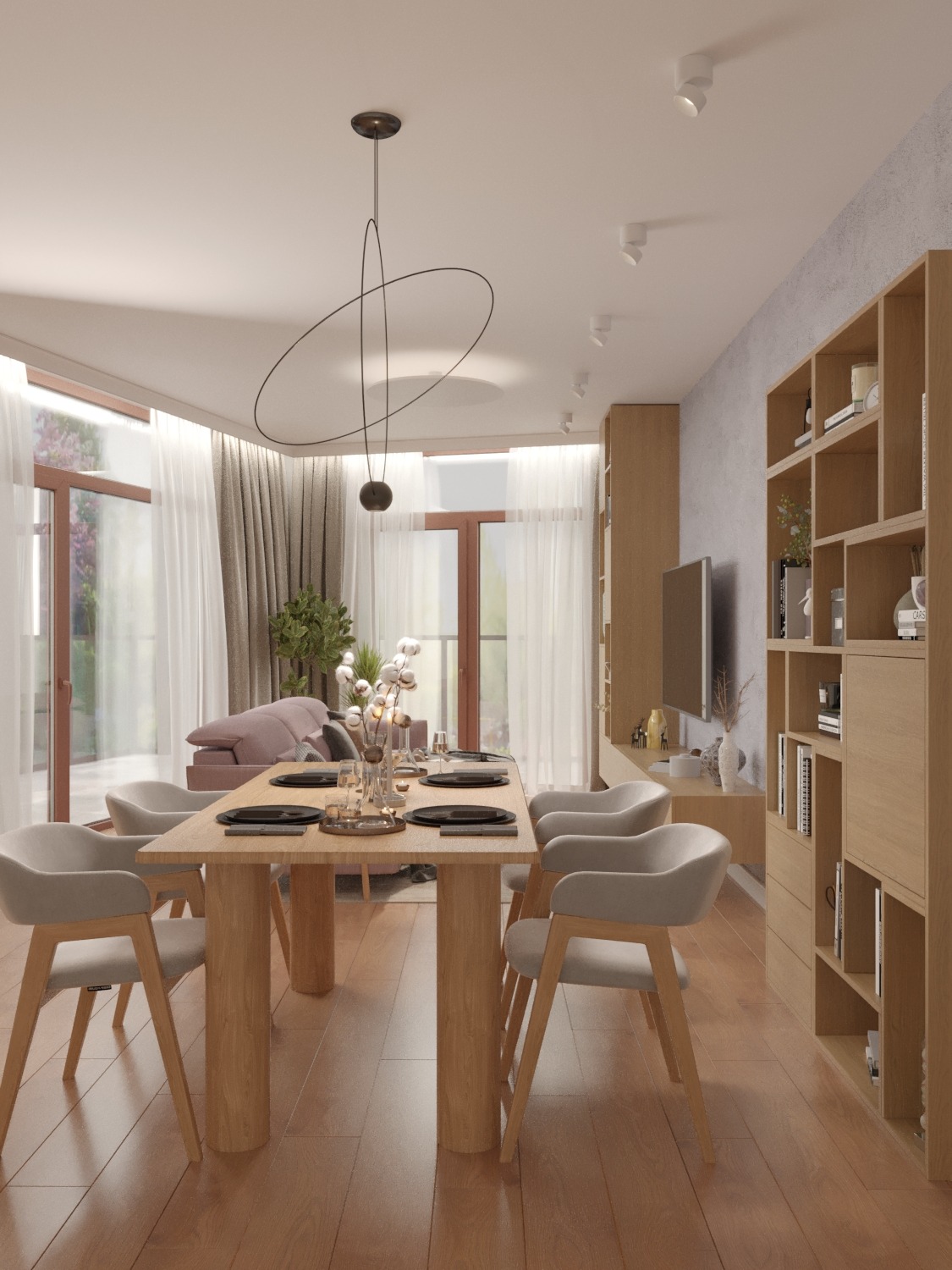 Wnętrze jadalni z drewnianym stołem i krzesłami w odcieniach beżu. Nad stołem wisi nowoczesna lampa z czarnymi okręgami. W tle regał i TV.