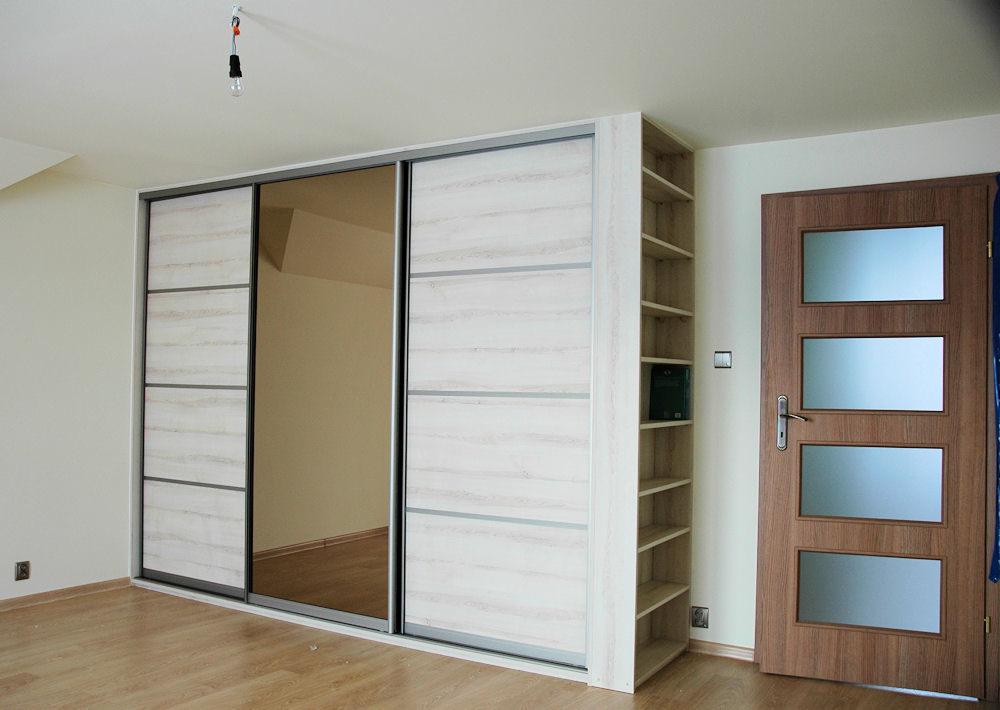 Wnętrze pokoju z dużą szafą przesuwną z lustrem, regałem z półkami i drewnianymi drzwiami z przeszkleniami, widok na podłogę z paneli.