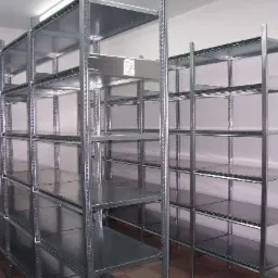 Metalowe regały magazynowe z perforowanymi słupkami, ustawione w rzędach w pomieszczeniu o jasnych ścianach.