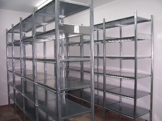 Metalowe regały magazynowe z perforowanymi słupkami, ustawione w rzędach w pomieszczeniu o jasnych ścianach.