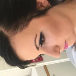 Profil twarzy kobiety z ciemnymi włosami i intensywnym, granatowym makijażem oczu oraz różowymi ustami. Widoczny delikatny kontur twarzy i podkreślone brwi.