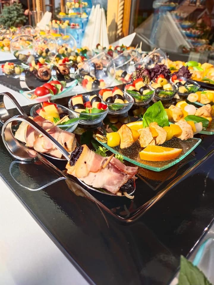 Elegancki catering w Elblągu: Różnorodne przekąski na szklanych i metalowych naczyniach, owoce, mięso, warzywa. Bogata oferta kulinarna na przyjęcie.