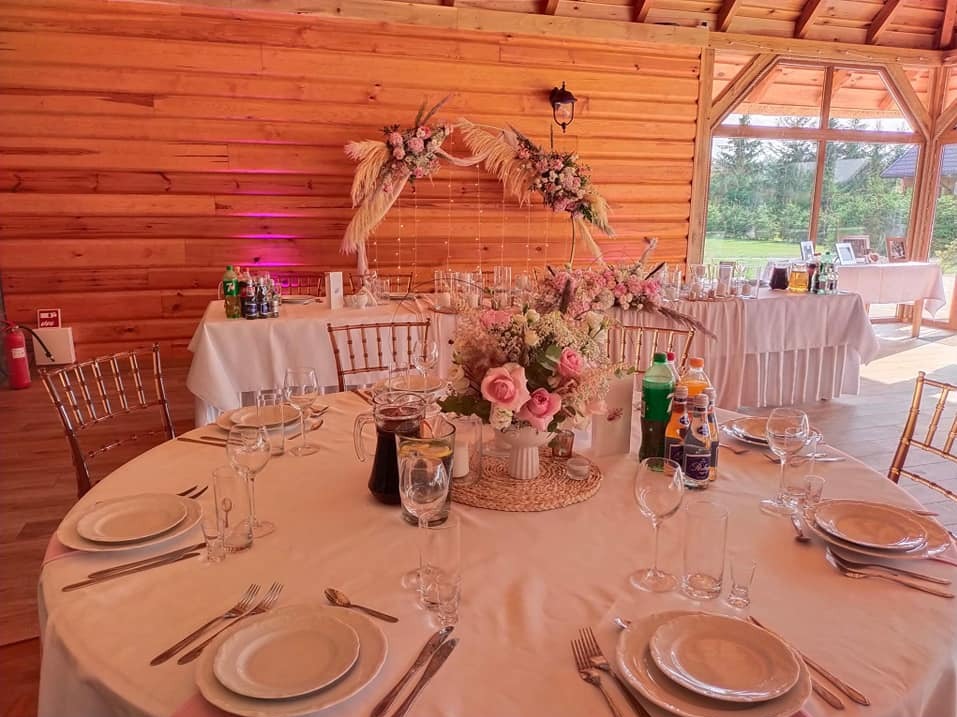 Dekoracja stołu weselnego w drewnianej sali: kwiaty, zastawa, napoje. Romantyczny wystrój z drewnianym tłem i oświetleniem.