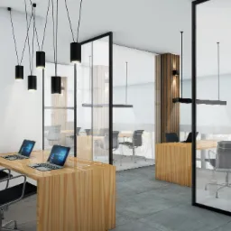 Nowoczesne biuro z drewnianymi biurkami, krzesłami na kółkach, szklanymi ścianami działowymi i minimalistycznym oświetleniem w postaci czarnych tub zawieszonych na cienkich kablach.