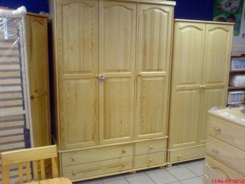 Jasne drewniane szafy z szufladami w dolnej części, widoczne również fragmenty krzesła i komody, całość w jasnym oświetleniu.