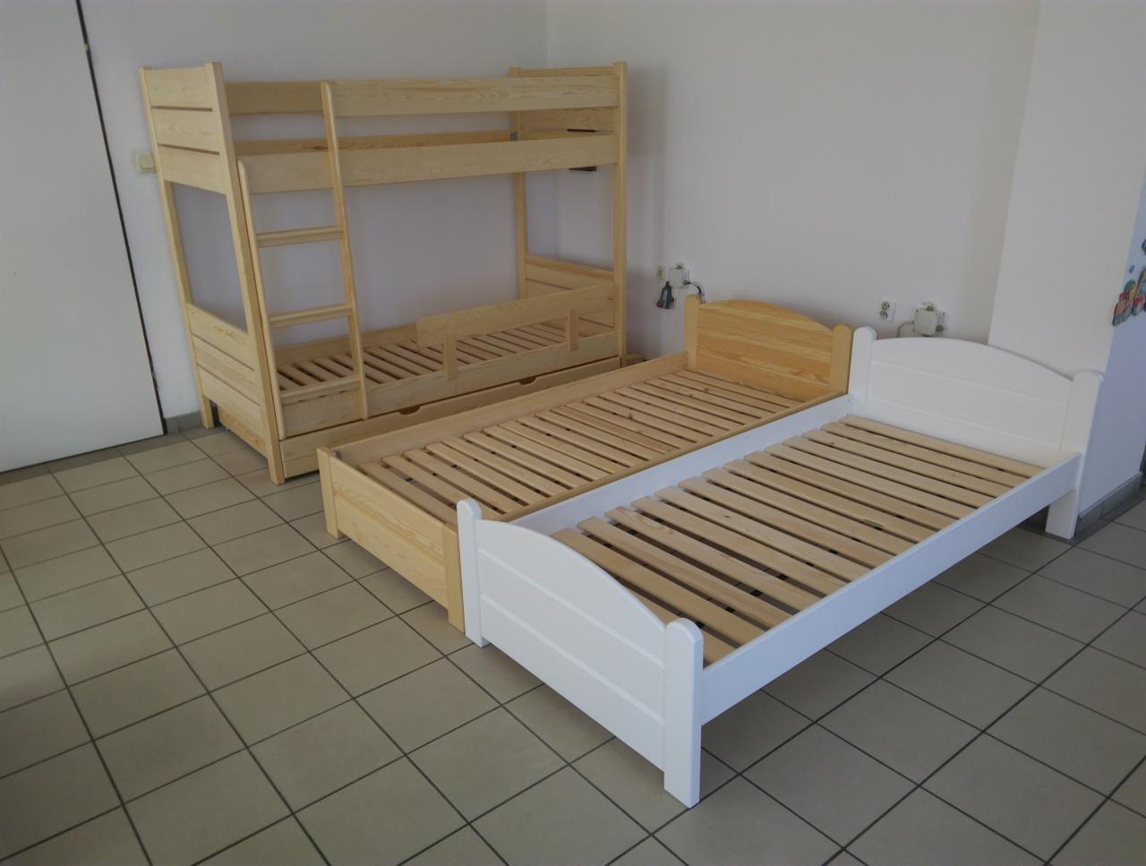 Dwuosobowe łóżko piętrowe z drewna sosnowego obok pojedynczego łóżka z drewnianym zagłówkiem i białą ramą, ustawione na kafelkach podłogowych.