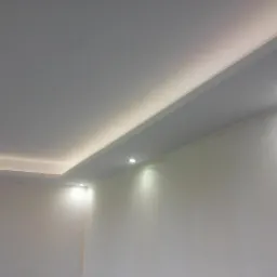 Nowoczesny sufit podwieszany z oświetleniem LED punktowym i listwami LED, ściany przygotowane do malowania.