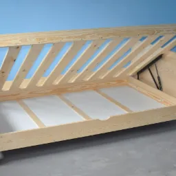 Rama łóżka z drewna sosnowego z podnoszonym stelażem i pojemnikiem na pościel, widoczne mechanizmy podnoszące i białe płyty wewnątrz.