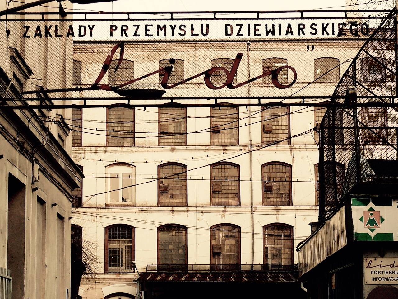 Budynek Zakładów Przemysłu Dziewiarskiego 'Lido' z widoczną metalową konstrukcją z nazwą zakładu na tle fasady z oknami.