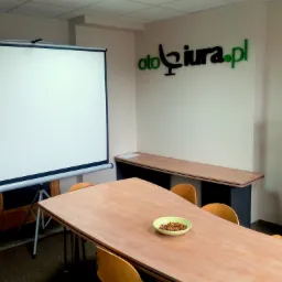 Sala konferencyjna z projektorem, stołem z przekąskami i logo firmy na ścianie.