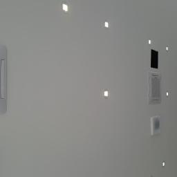 F.U.Arek Arkadiusz Wielosz - Biała ściana z zamontowanymi kasetonowymi jednostkami wewnętrznymi klimatyzacji i punktowymi lampami LED, widok pod kątem.