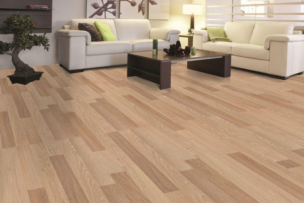 Jasna podłoga z paneli ułożonych w jodełkę francuską w salonie z białymi sofami i stolikiem kawowym.