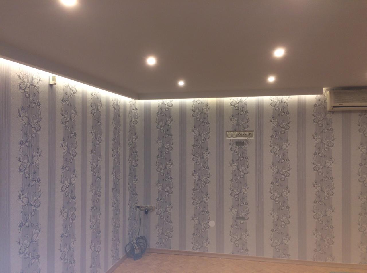 Pokój po remoncie z nową tapetą w pionowe pasy z motywem kwiatowym, podświetlany sufit i parkiet na podłodze, widoczny klimatyzator.