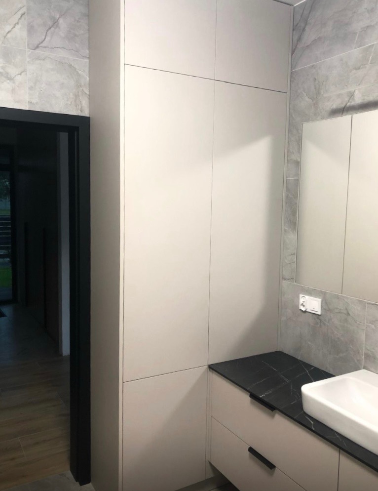 Jasna szafa łazienkowa na wymiar z czarnym blatem i umywalką nablatową, Radomsko. Minimalistyczny design, szare płytki imitujące marmur w tle.