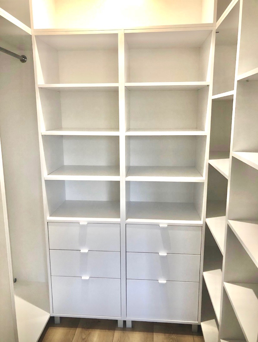 Biała szafa wnękowa z półkami i szufladami, widok z wnętrza. Minimalistyczny design, jasne oświetlenie, drewniana podłoga. Element garderoby.