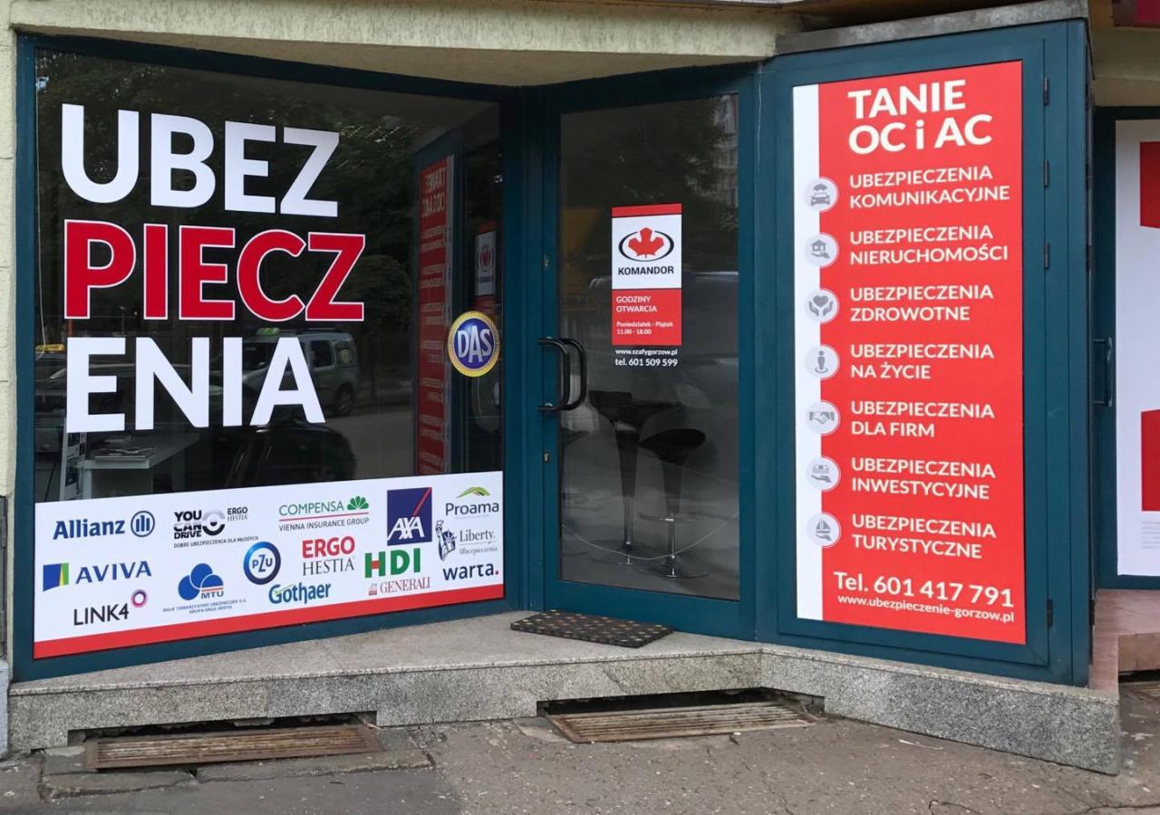 Wejście do biura ubezpieczeń w Gorzowie Wielkopolskim z widocznymi naklejkami informacyjnymi na szybach oraz logo różnych towarzystw ubezpieczeniowych.