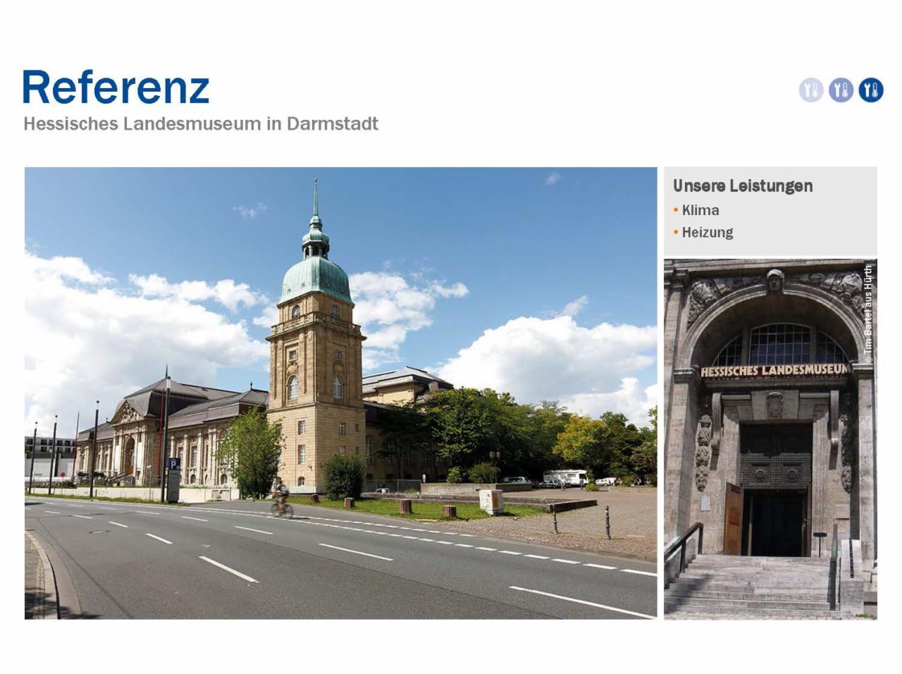 Zdjęcie budynku Hessisches Landesmuseum w Darmstadt z wieżą zwieńczoną zieloną kopułą, widok od strony ulicy z rowerzystą, obok fragment z informacją o klimatyzacji i ogrzewaniu.