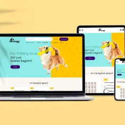 Responsywna strona WWW sklepu zoologicznego na laptopie i smartfonie. W tle cień liści. Projekt strony z psem rasy Corgi. Elementy UI w języku niemieckim.