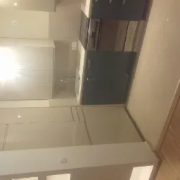 Nowoczesna kuchnia z beżowymi szafkami na wysoki połysk, ciemnozielonymi szafkami dolnymi i srebrną kuchenką, widok z dołu.