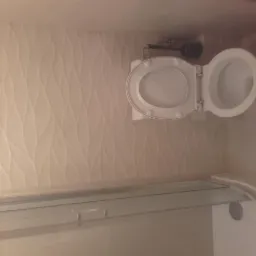 Nowoczesna toaleta z otwartą klapą w łazience wykończonej płytkami z subtelnym wzorem fal.