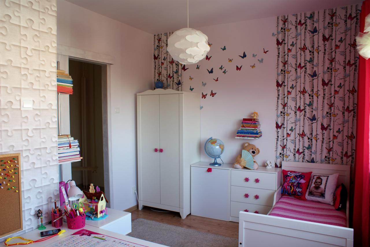 Pokój dziecięcy w Zduńskiej Woli z białymi meblami, tapetą w motyle i wzorem puzzli na ścianie, oświetlony lampą w kształcie chmury.