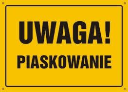 Żółta tabliczka ostrzegawcza z czarnym napisem 'UWAGA! PIASKOWANIE' w czarnej ramce, przymocowana czterema śrubami w rogach.