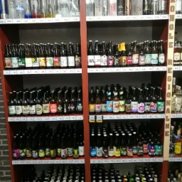 Półki wypełnione różnorodnymi butelkami piwa i wódki w sklepie w Jarosławiu, z widocznymi cenami na etykietach.