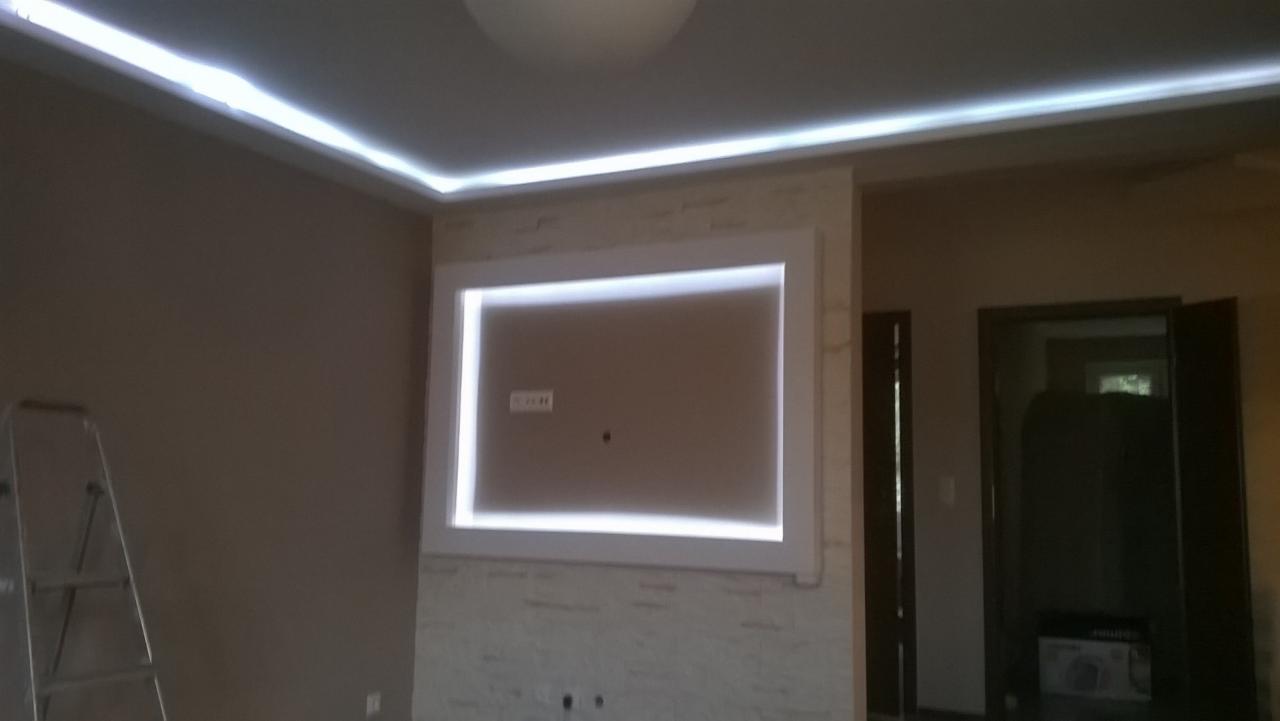 Pokój z zamontowanym oświetleniem LED w suficie i wnęce na ścianie, drabina oparta o ścianę, widoczne gniazdka elektryczne.