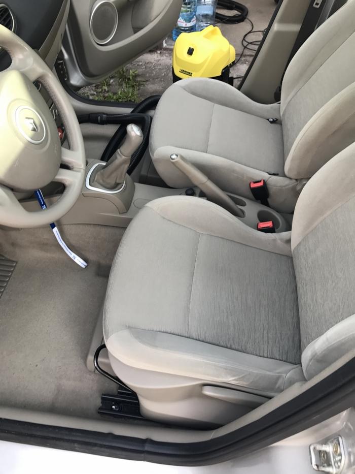 Wnętrze samochodu z beżową tapicerką podczas czyszczenia, widoczny odkurzacz Karcher, woda butelkowana i rura ssąca.