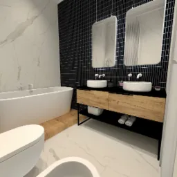 Nowoczesna łazienka z białymi marmurowymi płytkami, czarną mozaiką, dwiema owalnymi umywalkami nablatowymi na drewnianej szafce i wolnostojącą wanną.