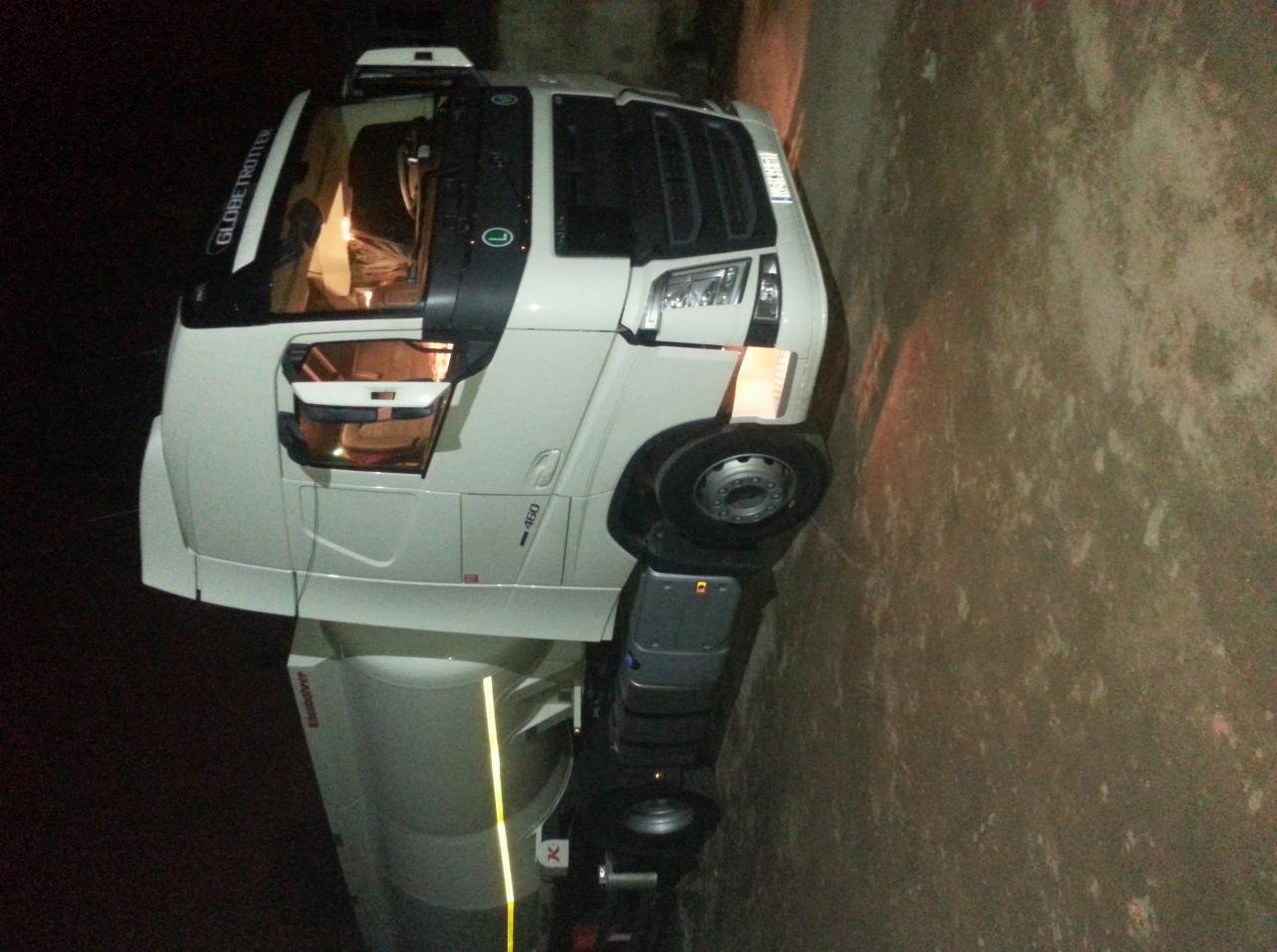 Biała ciężarówka Volvo FH 460 zaparkowana nocą na betonowym placu, widoczne odblaski i oświetlenie kabiny.