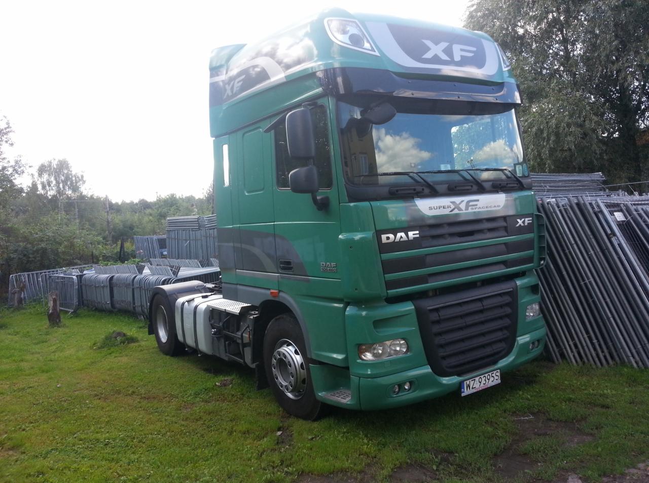 Zielony ciągnik siodłowy DAF XF na trawiastym terenie, z widocznymi metalowymi barierami w tle, rejestracja WZ 9395S.