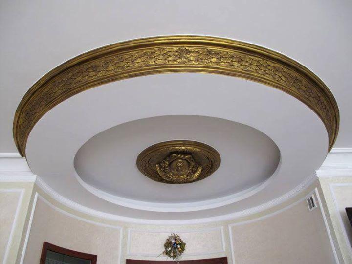 Okrągły sufit z dekoracyjną, złoconą sztukaterią i rozetą w centrum, widok z dołu.