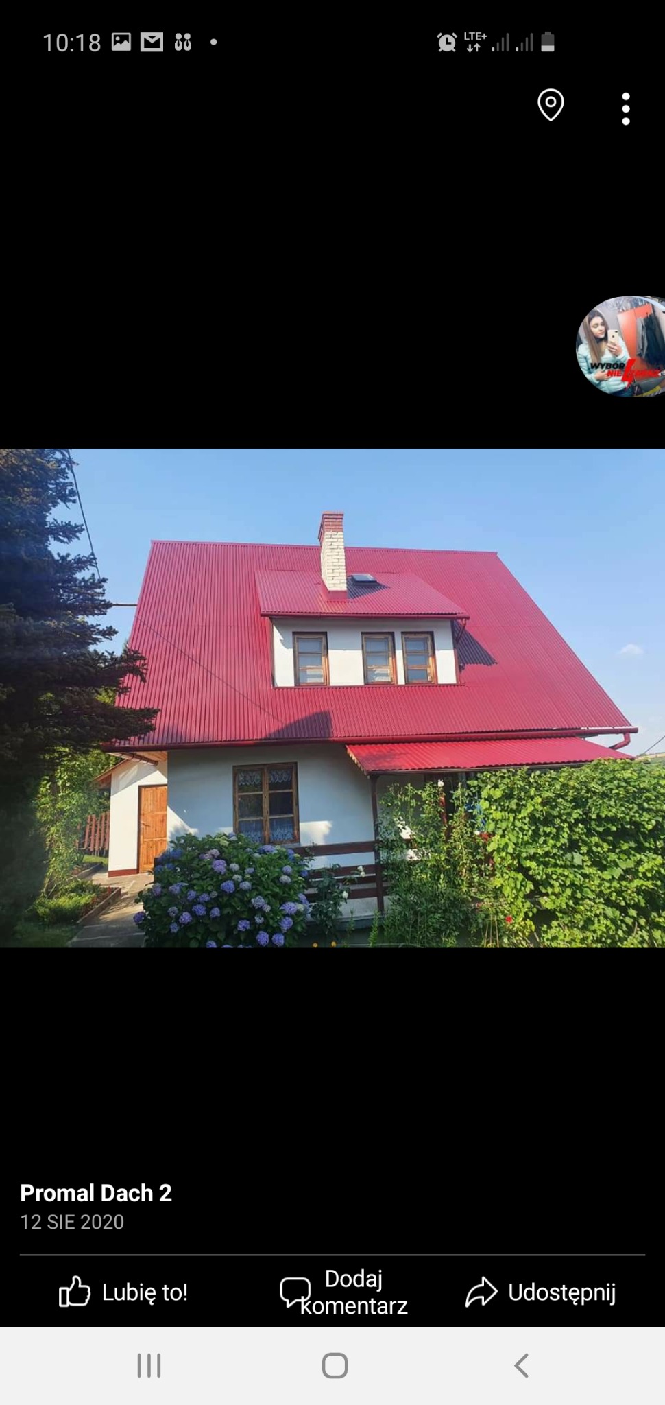 Dom jednorodzinny z nowym, czerwonym dachem z blachy trapezowej, widoczny komin i okna na poddaszu, hortensje w ogrodzie.