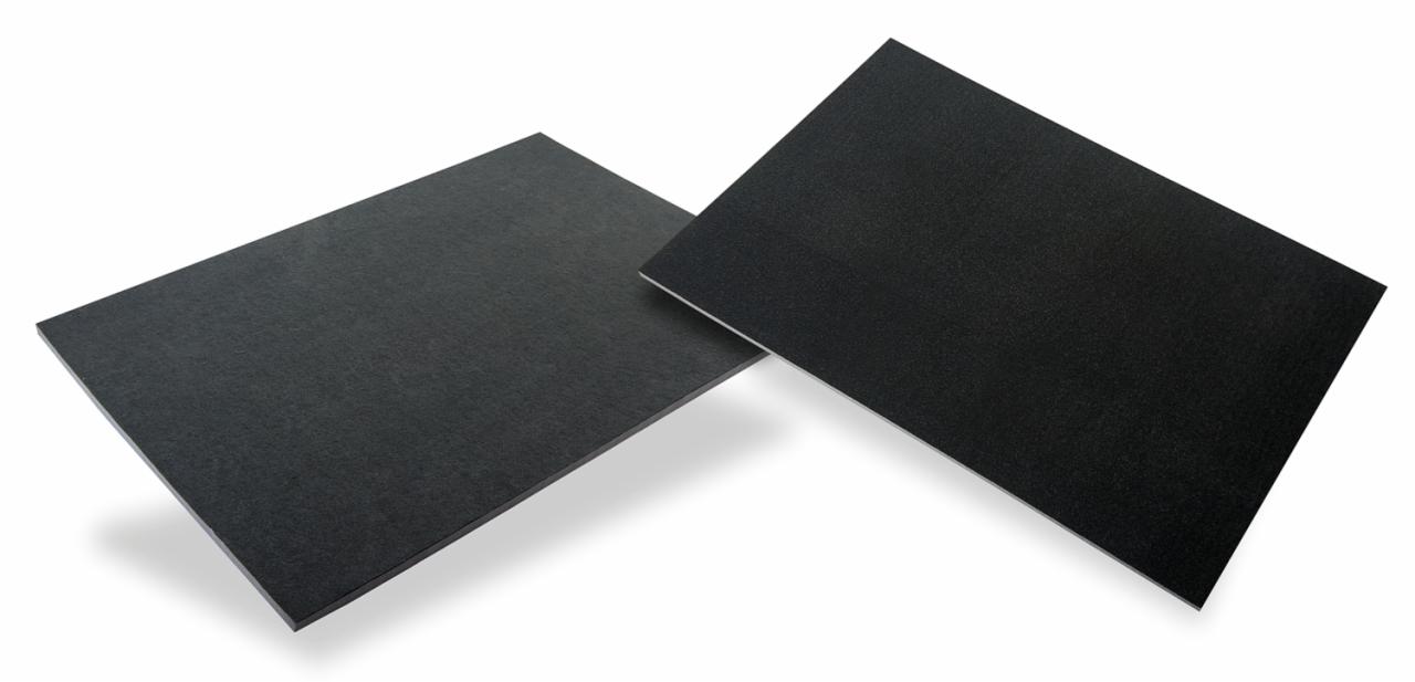 Dwa czarne, prostokątne arkusze materiału o szorstkiej fakturze, ułożone pod kątem na białym tle, rzucające cień.
