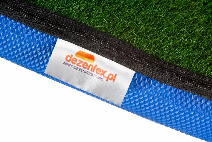 Mata dezynfekcyjna z niebieskim wzorem, zieloną imitacją trawy i czarnym zamkiem błyskawicznym, etykieta z logo dezenfex.pl.