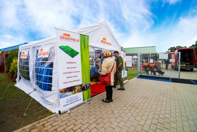 Stoisko targowe z prezentacją mat dezynfekcyjnych dla hodowców, z widocznym banerem reklamowym i osobami zwiedzającymi.